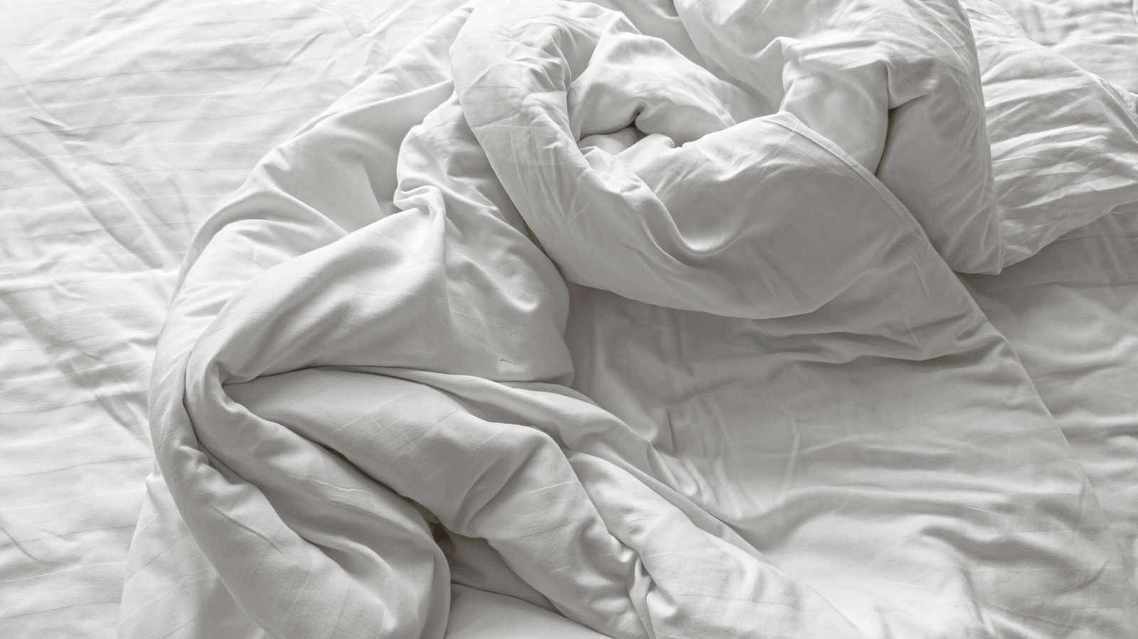 Crumpled white bedding inviting comfort and relaxation in a serene bedroom setting.