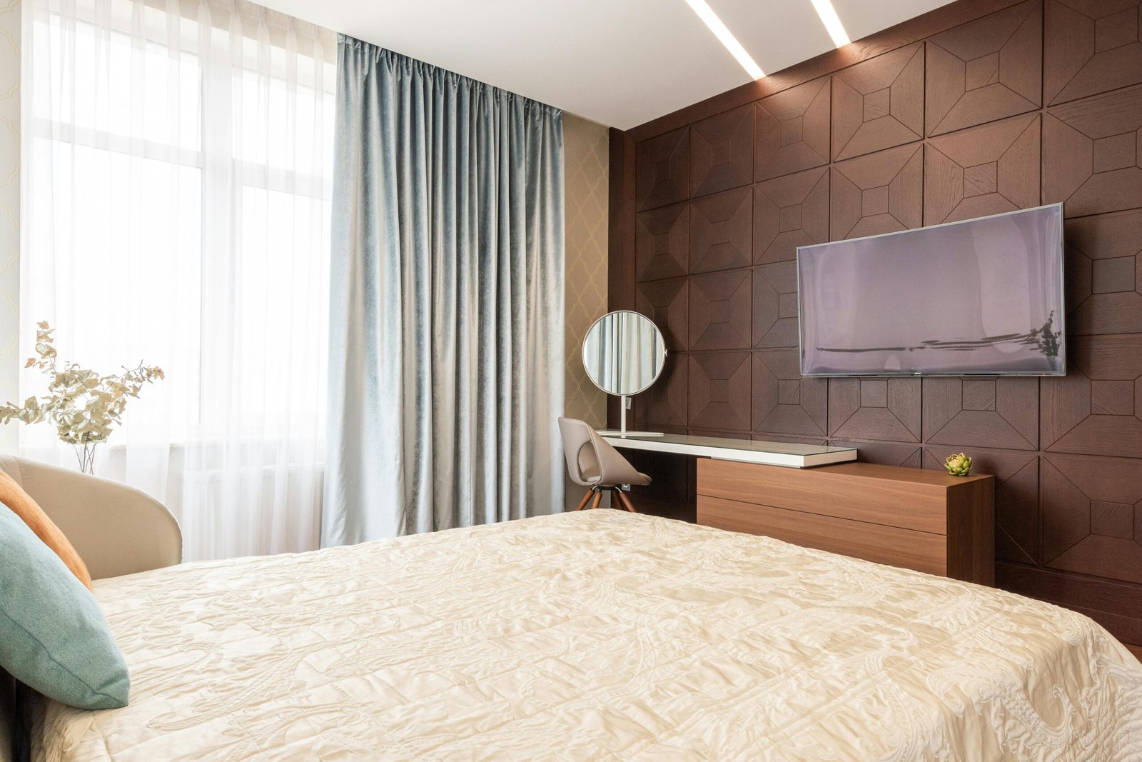 Stylish contemporary bedroom featuring a TV, desk, and elegant bedding. Ideal for relaxation.